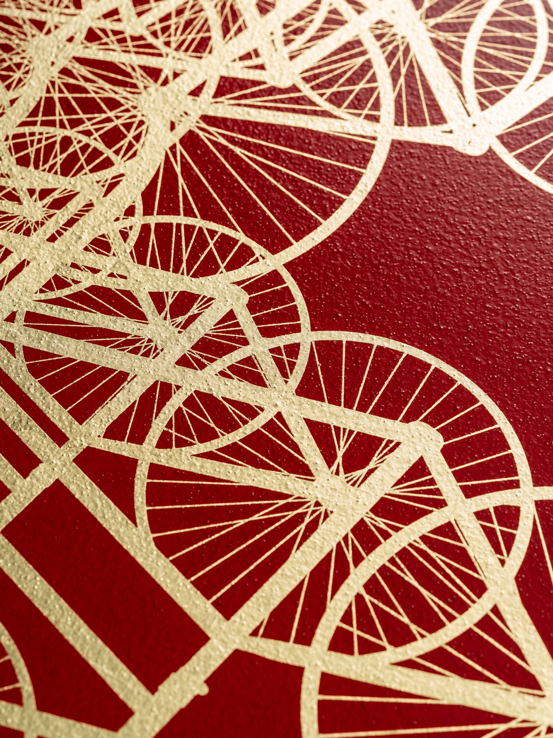 Abstract gold geometric pattern on a textured red background, featuring interconnected circles and lines resembling bicycle wheels.