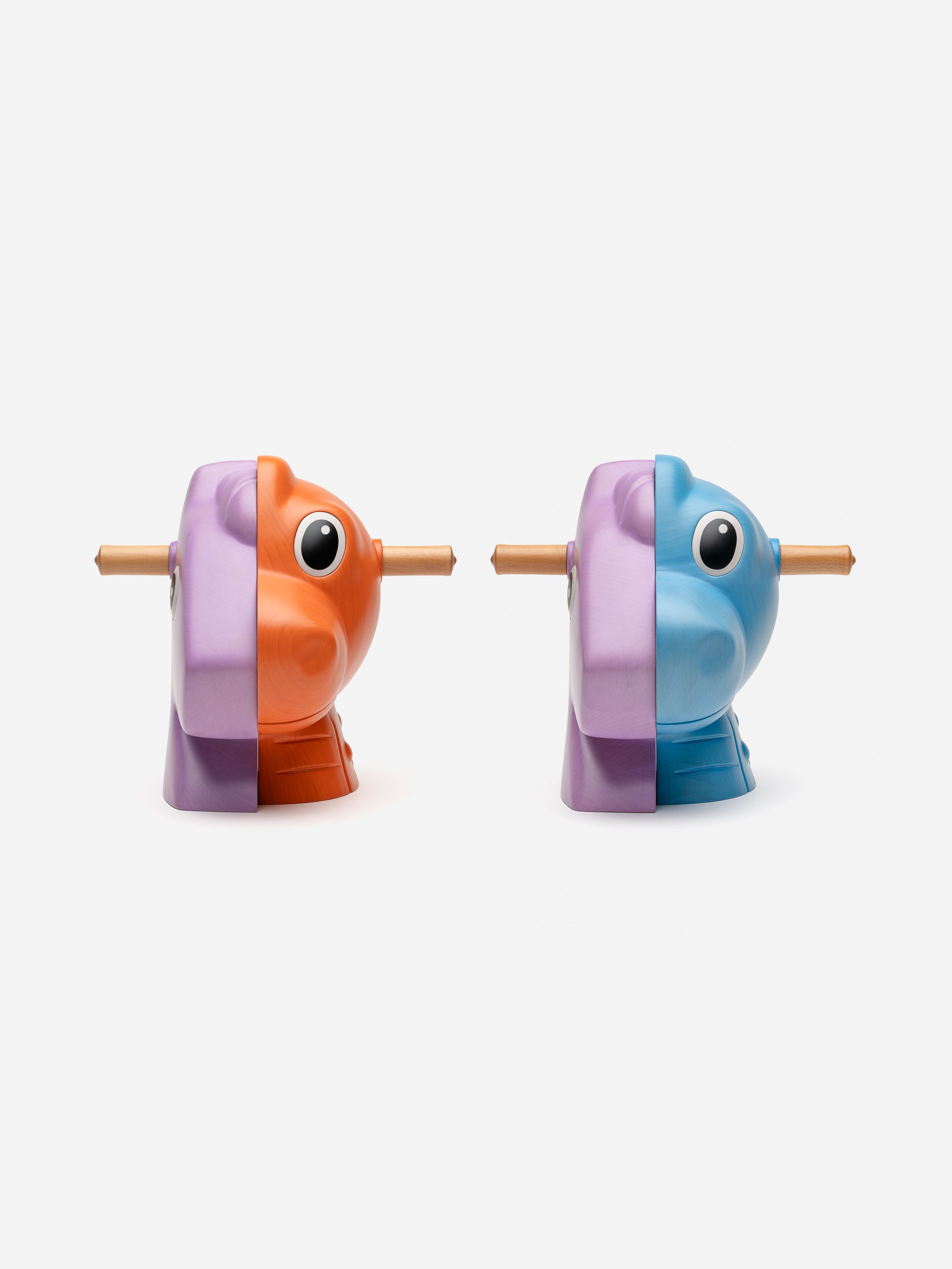 Two wooden toy split in half, one orange and pink, the other blue and pink with large eyes and a rod through the centre, on a white background.