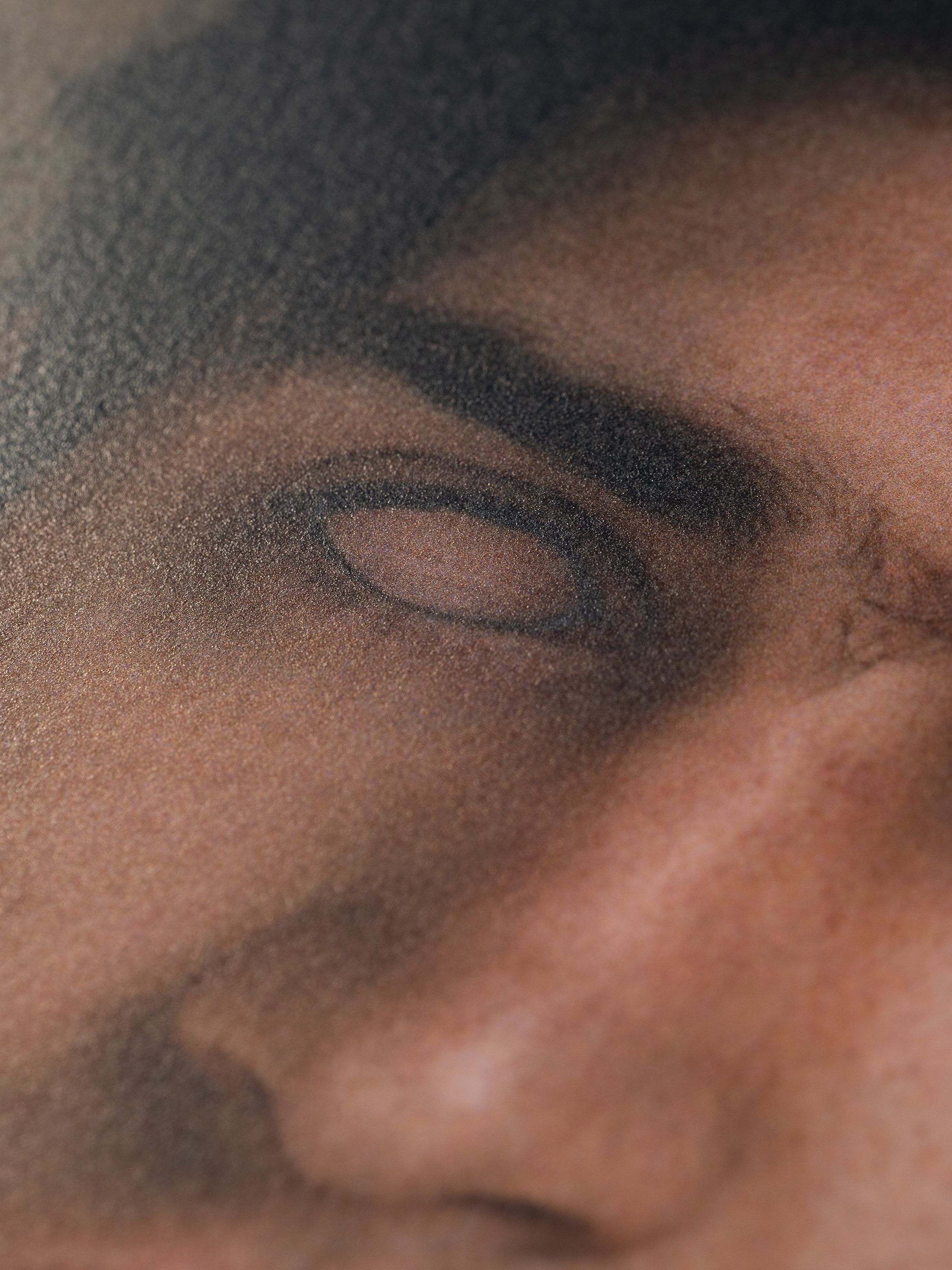 Close-up of a detailed printed image showing a person's eye and eyebrow, with visible texture and dot pattern from the print.