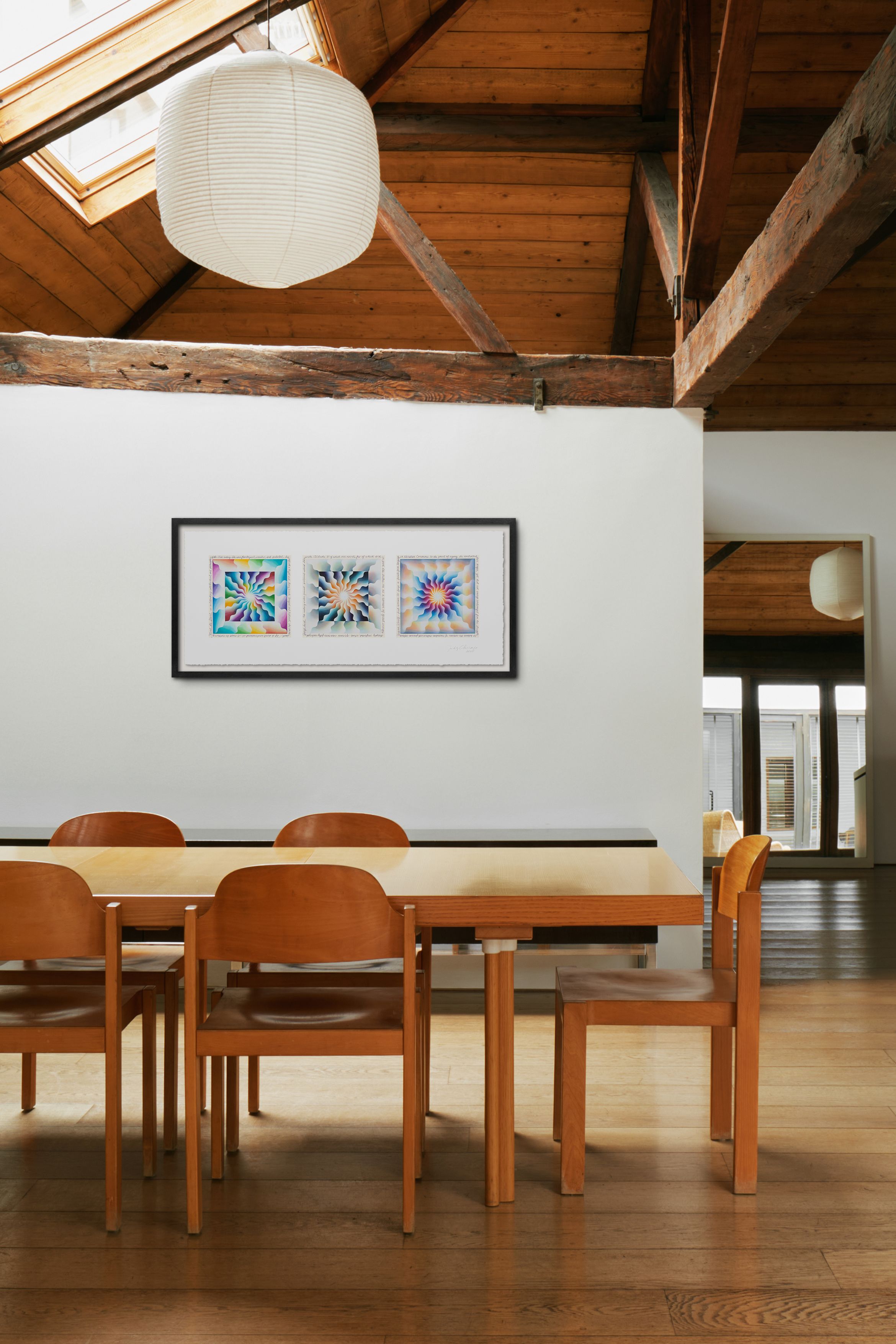 Dining area with wooden table and chairs, colourful artwork on white wall, wooden beams, and a paper lantern hanging from the ceiling.