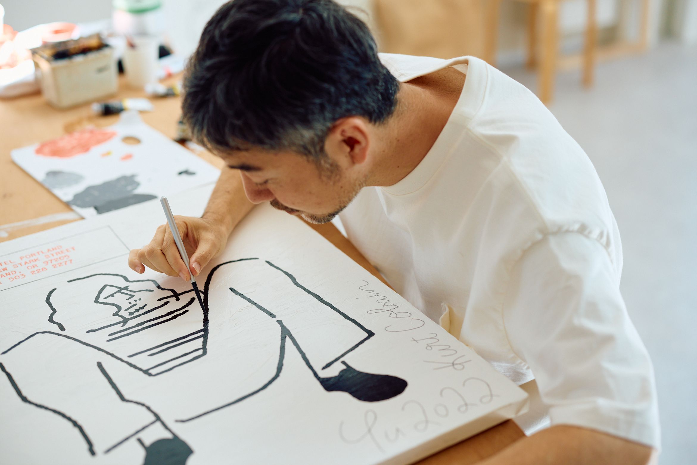 Yu Nagaba adding black line to a white canvas on the table surface