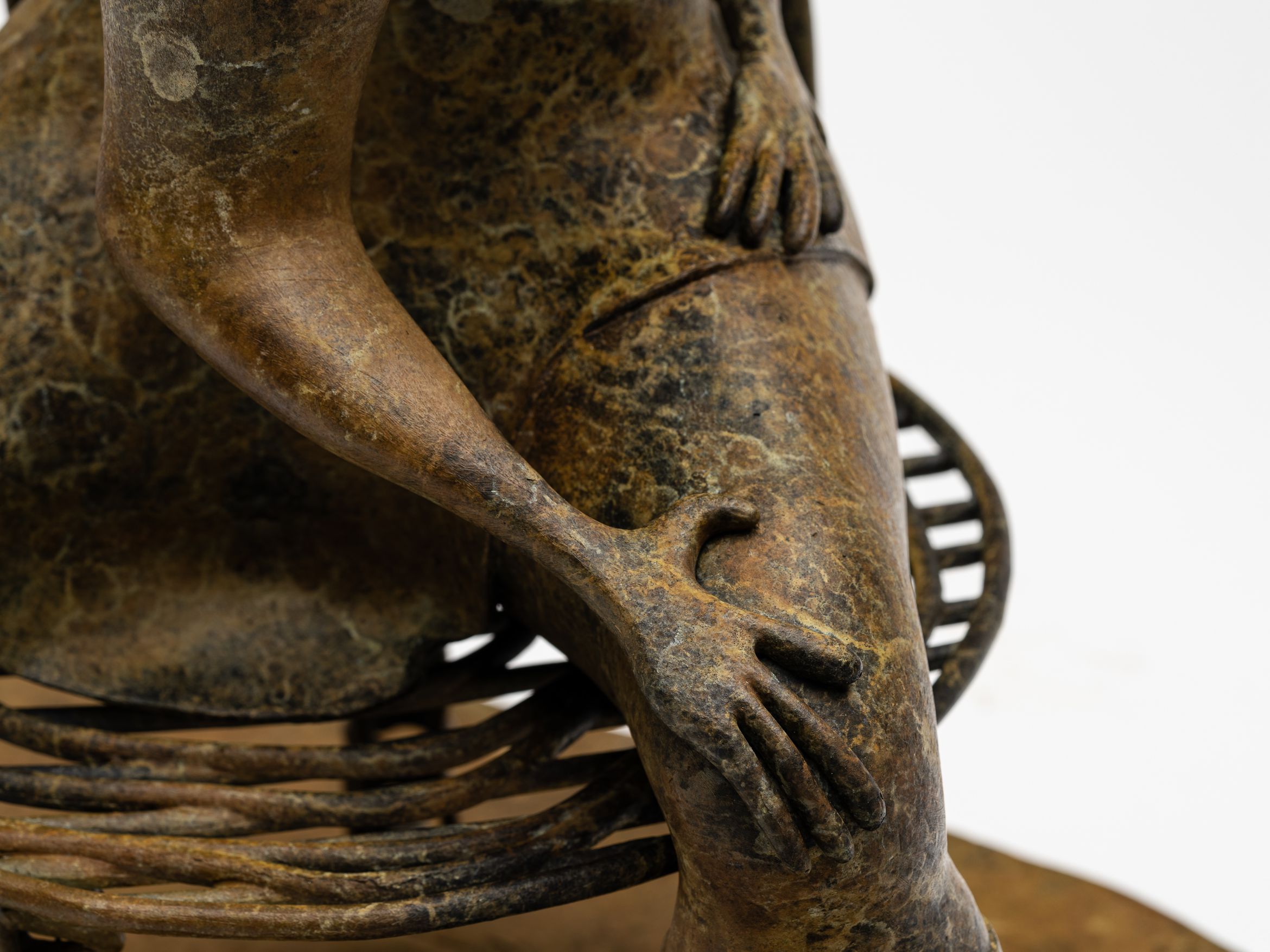 Bronze sculpture of seated woman with a hat