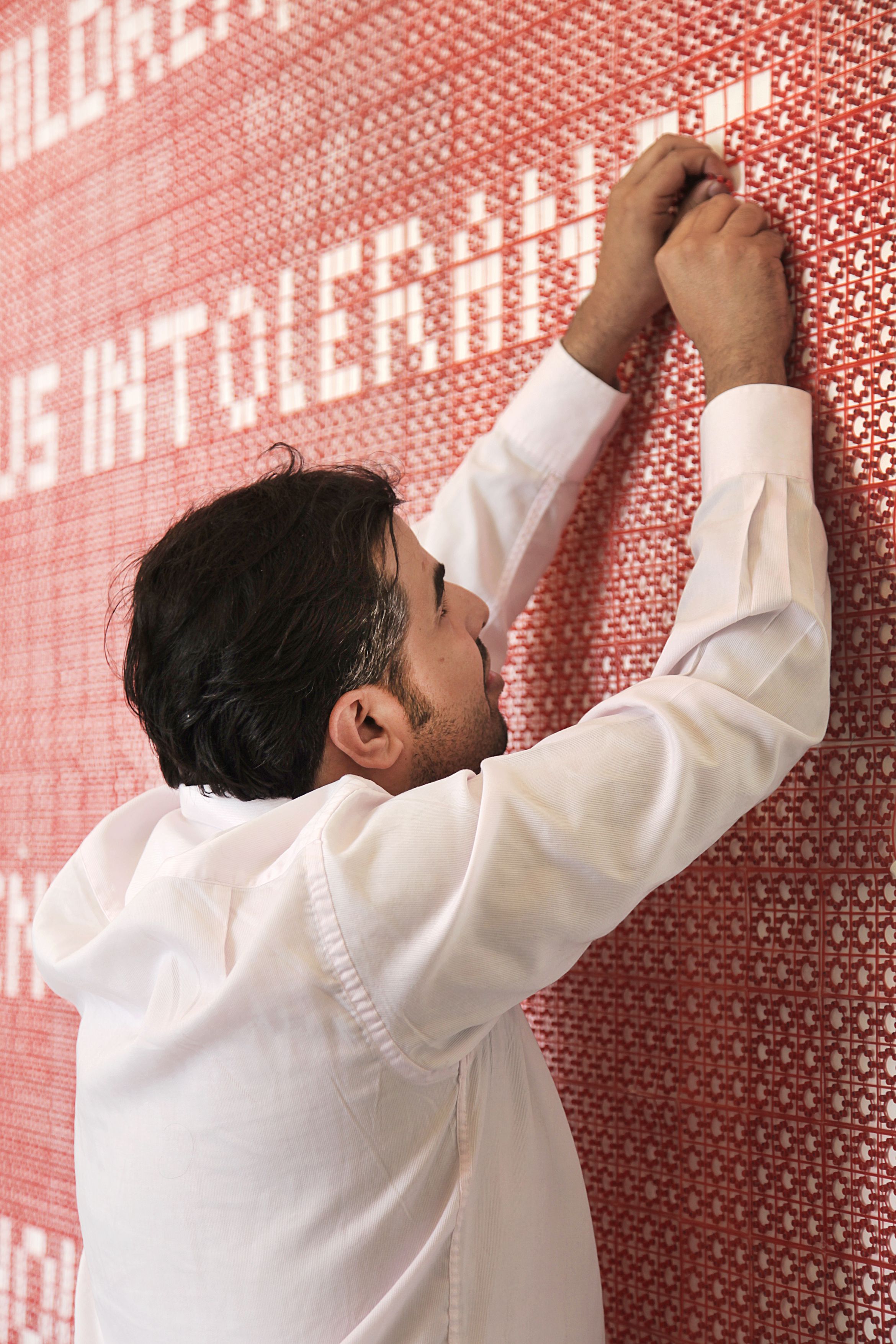 Saudi artist Ahmed Mater working on a large-scale, textured work as part of his famous Guncaps series.