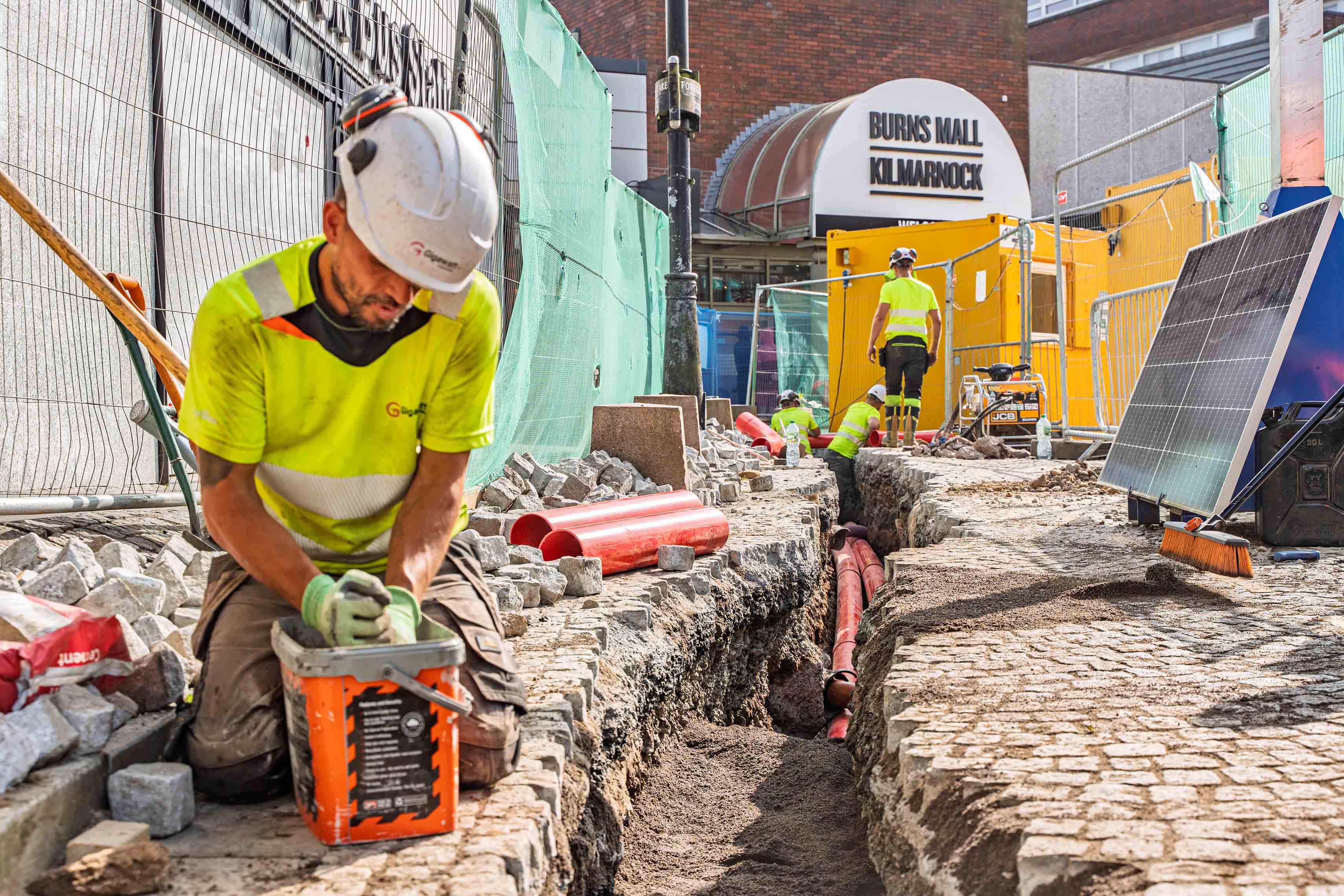 EV charging infrastructure installation at Burns Mall Kilmarnock - construction team deploying underground cables for electric bus depot charging system