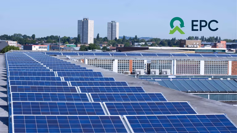 Rooftop solar panels on an industrial building with a cityscape and two tall buildings in the background. EPC logo in the top right corner.