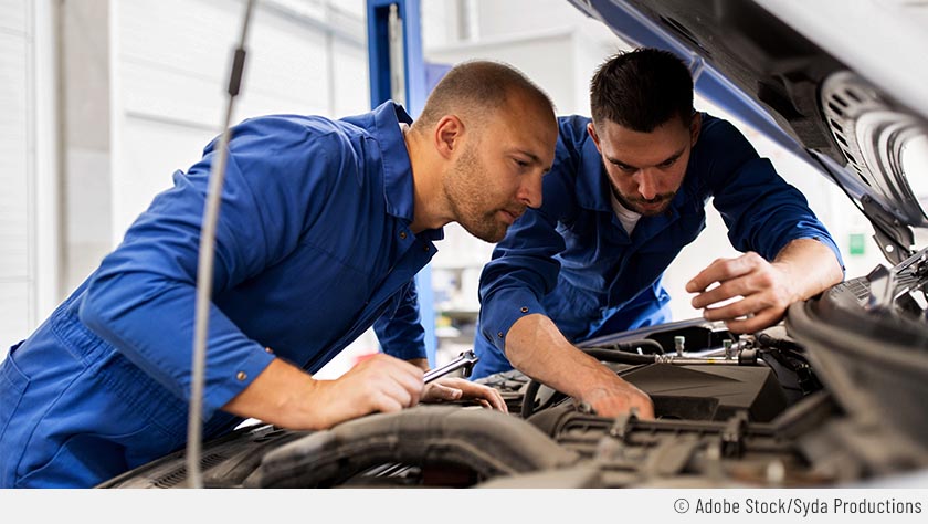 Deux garagistes installant des pièces détachées dans le capot d'une voiture