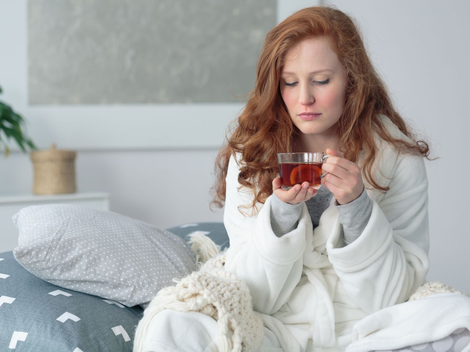 Eine Frau sitzt auf dem Sofa und hält eine Tasse Tee in der Hand.