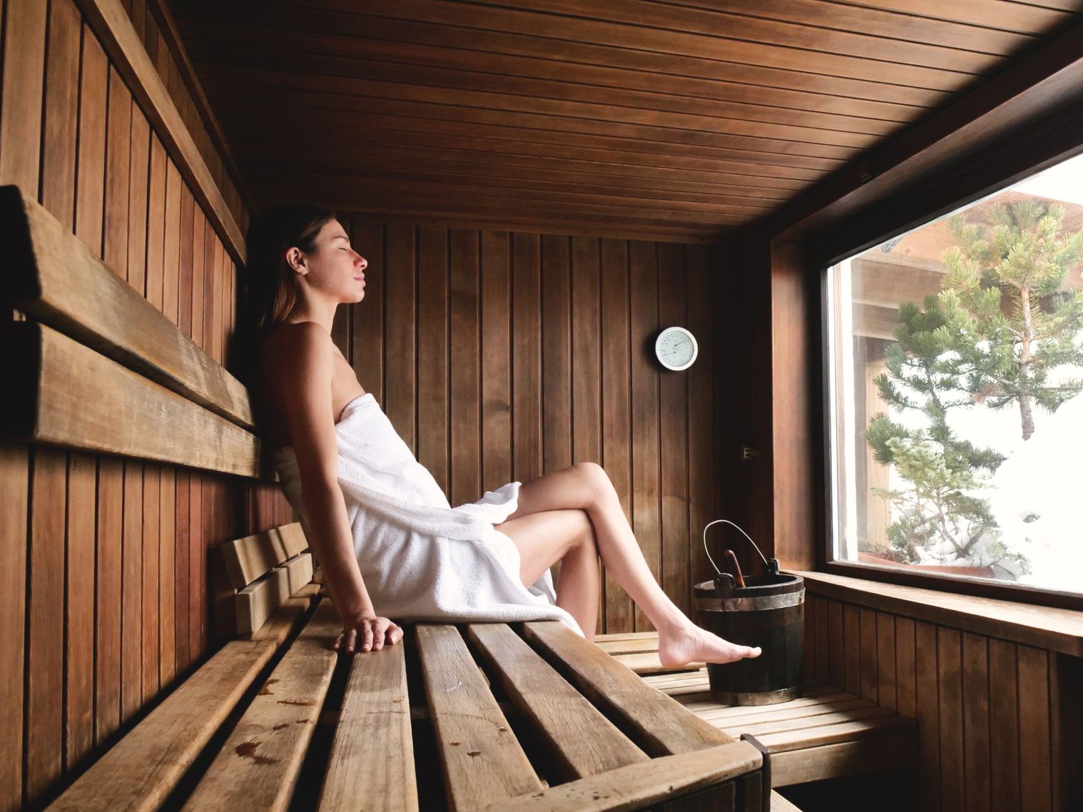 Eine Frau sitzt mit Handtuch in der Sauna