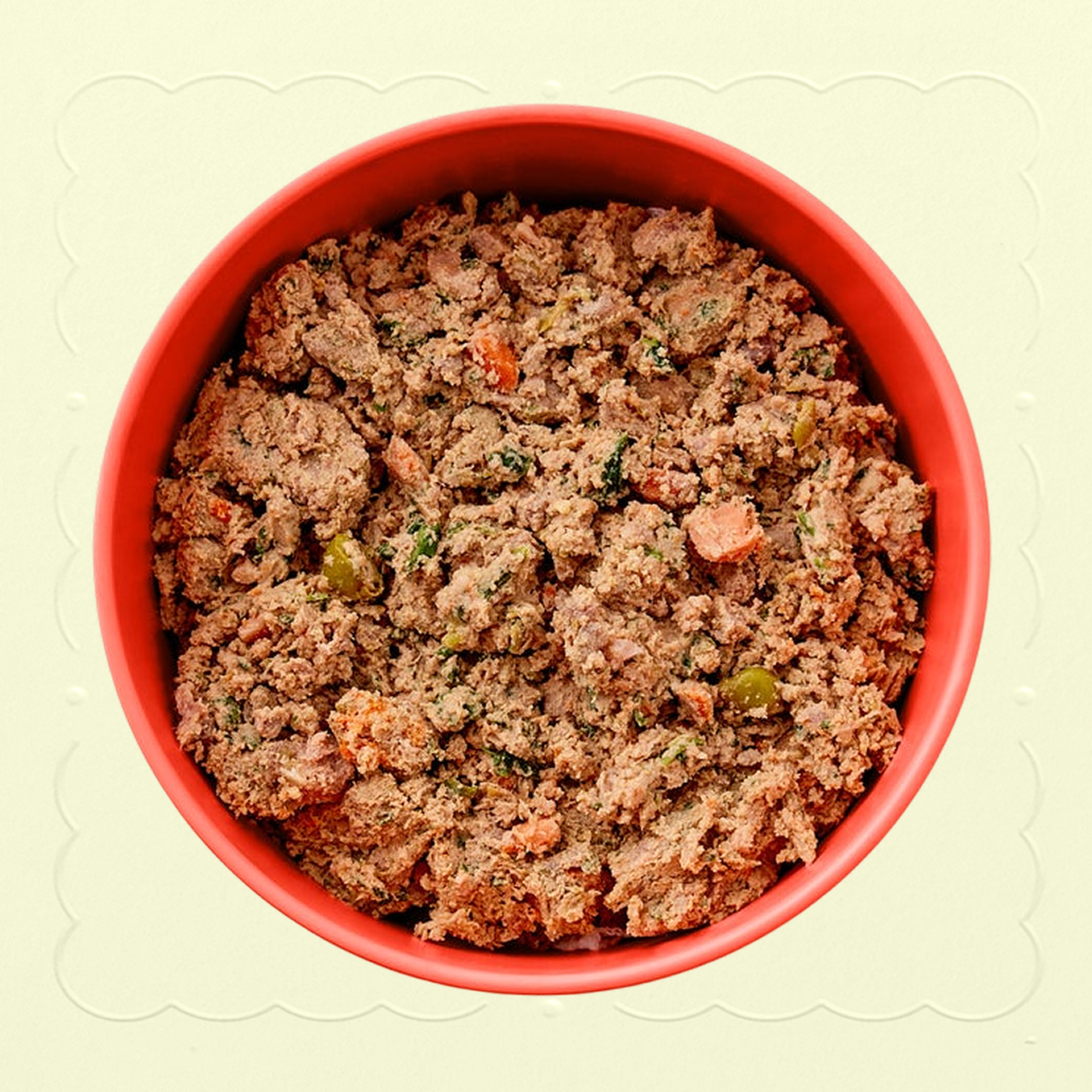 A red bowl of fresh beef recipe with sweet potatoes Ollie recipe, with peas, kale, and sweet potato chunks visible. Bowl placed on a cream background with an embossed pattern