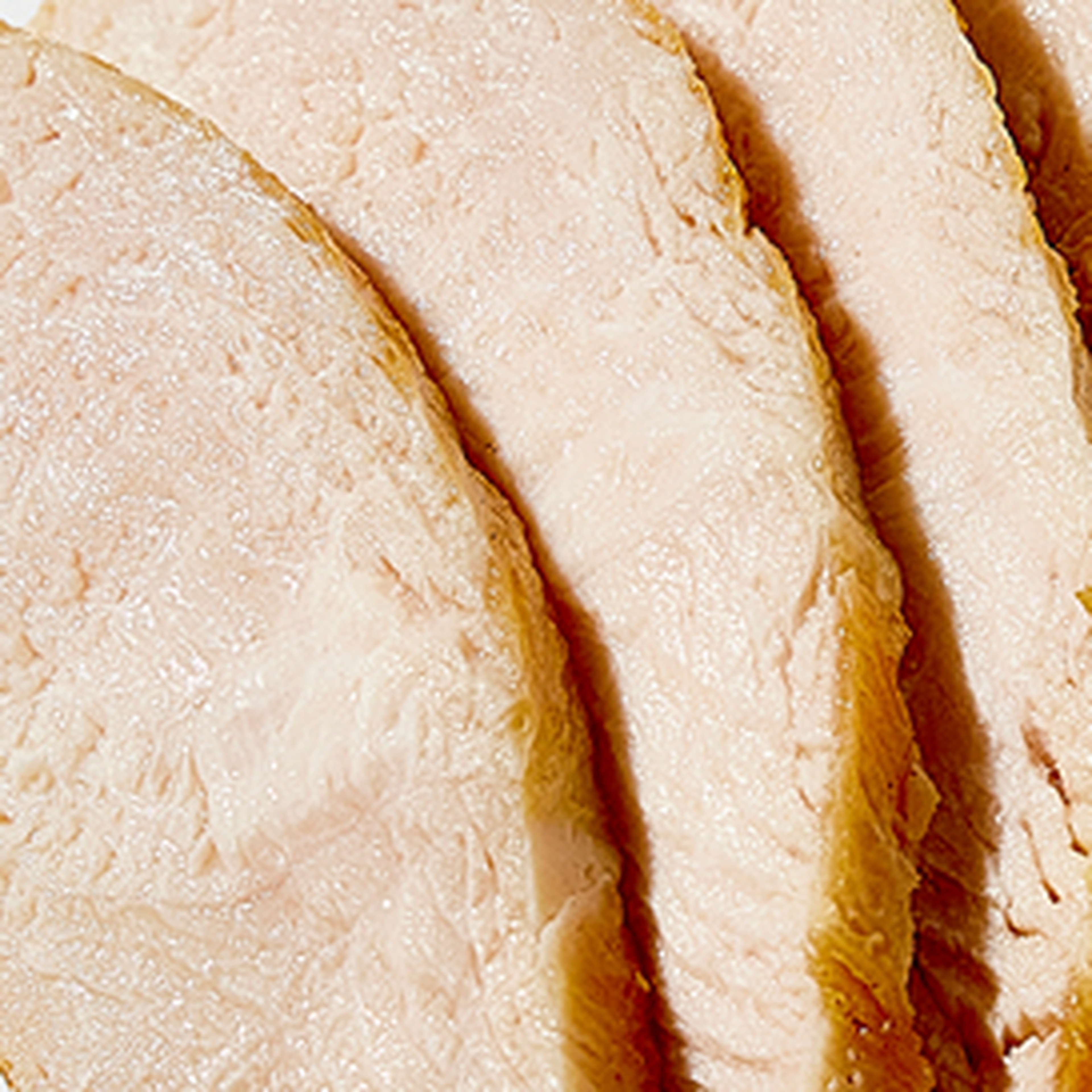 Close-up of four slices of turkey breast with a light, moist texture, arranged neatly.