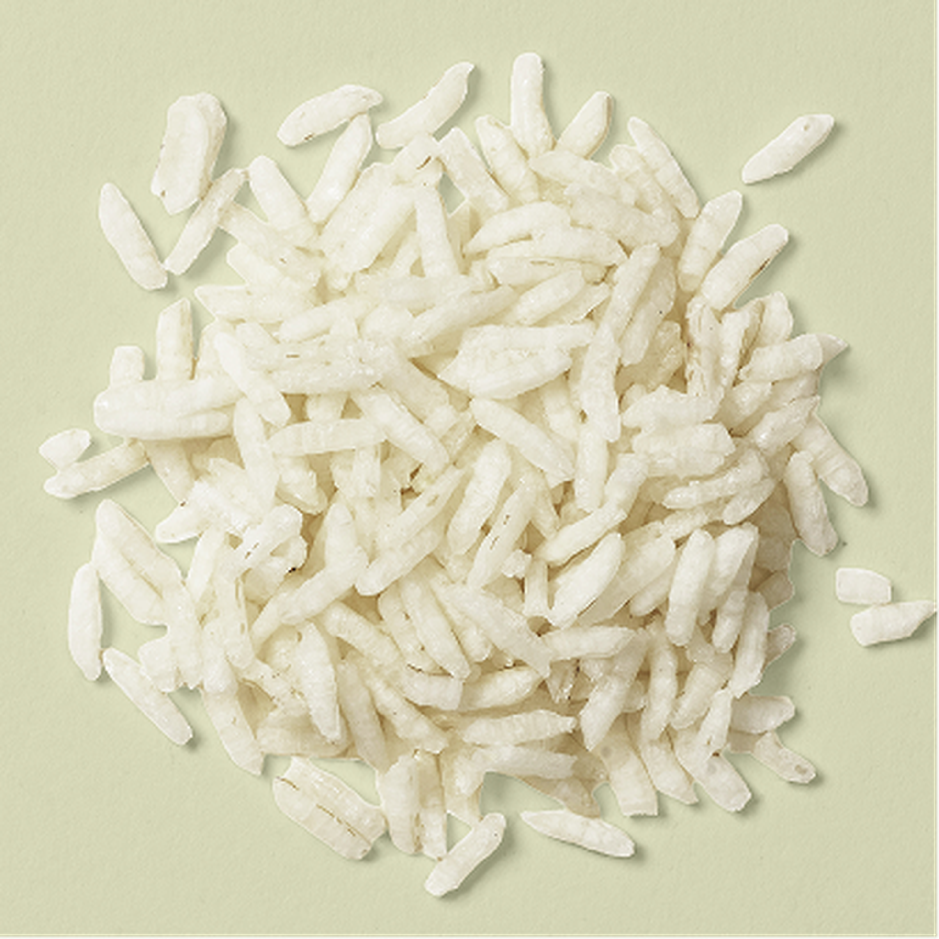 A pile of white puffed rice on a light green background, showcasing their elongated and airy texture.