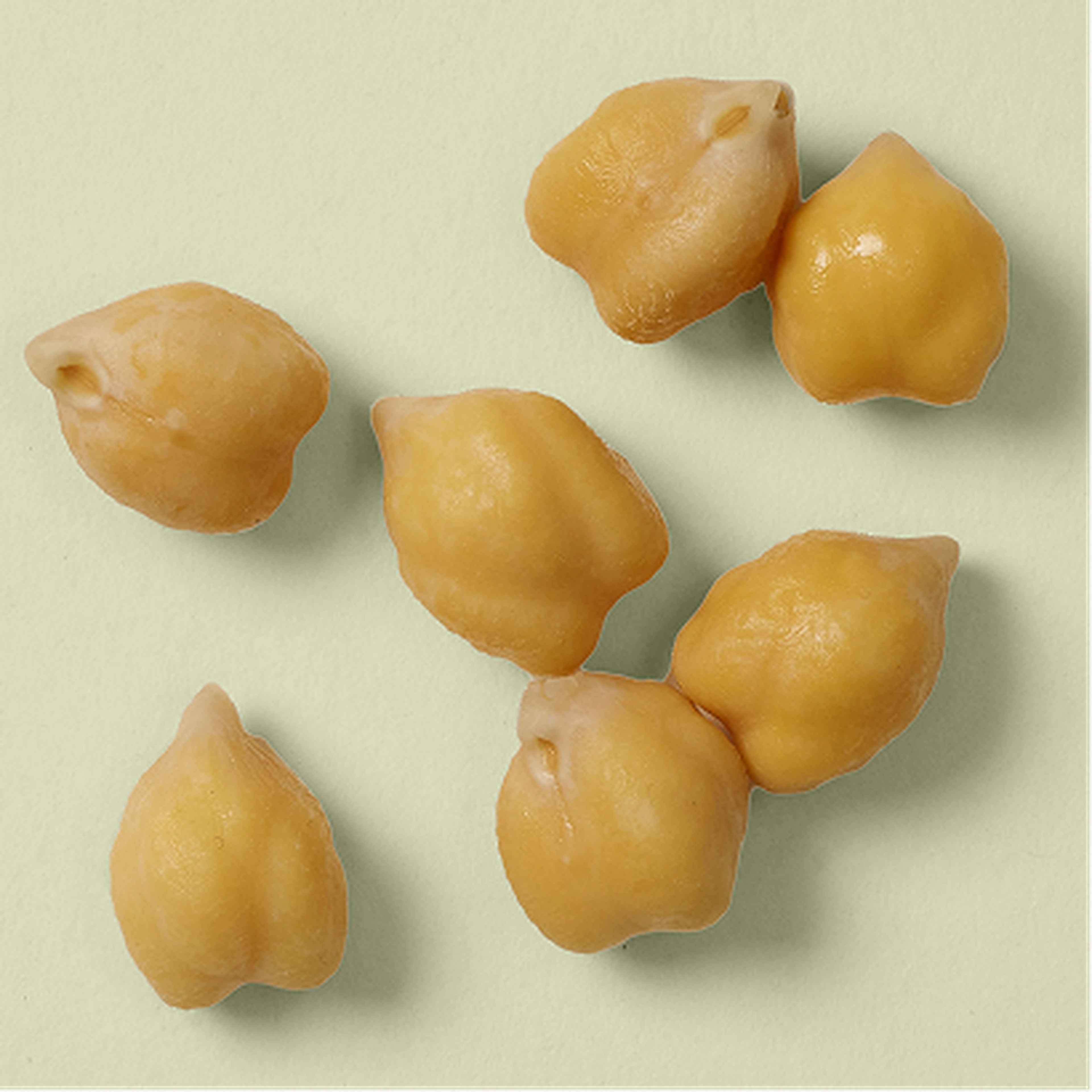 Six chickpeas scattered on a light green surface.