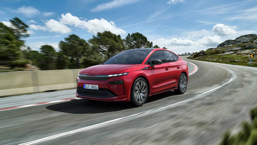 Red Skoda Elroq driving along a mountainous road with blue skies