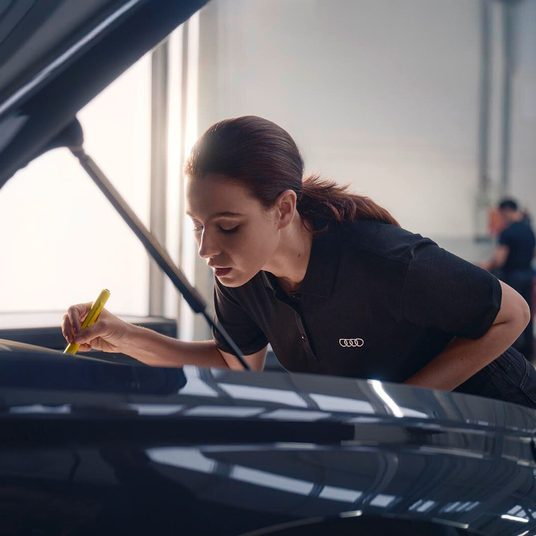 A woman working on an Audi in a workshop