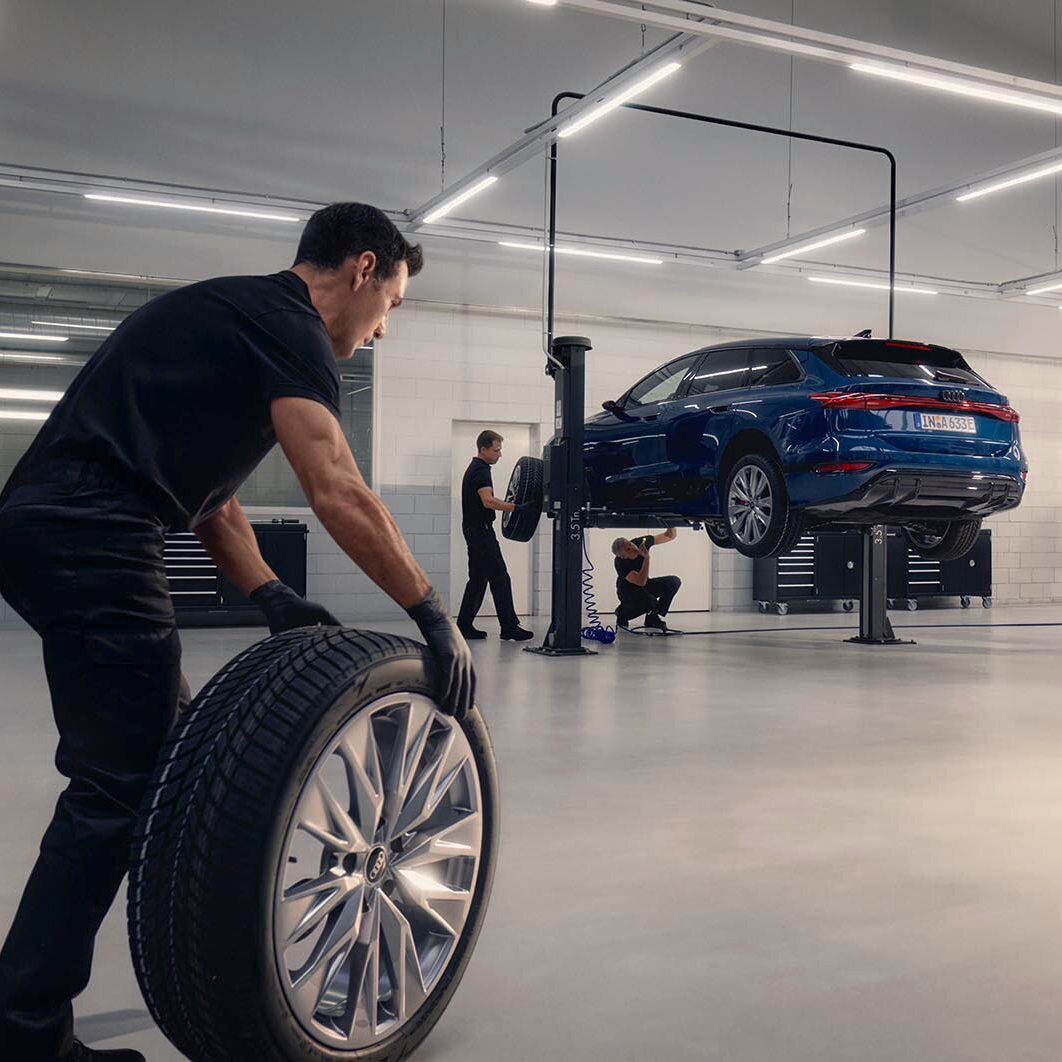 A man rolling a tyre through the an Audi workshop
