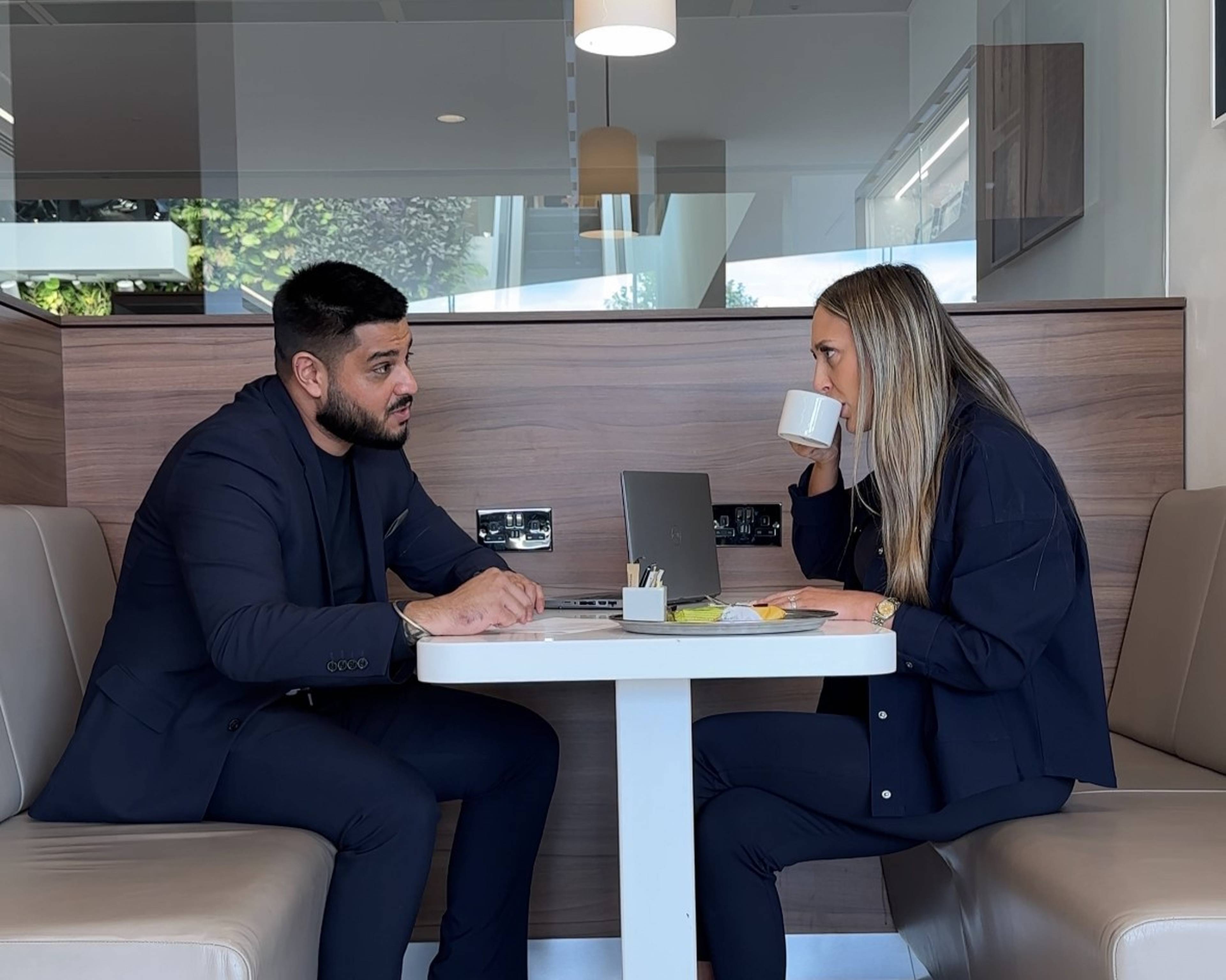 A picture of a car buyer talking to a client sitting at a table.