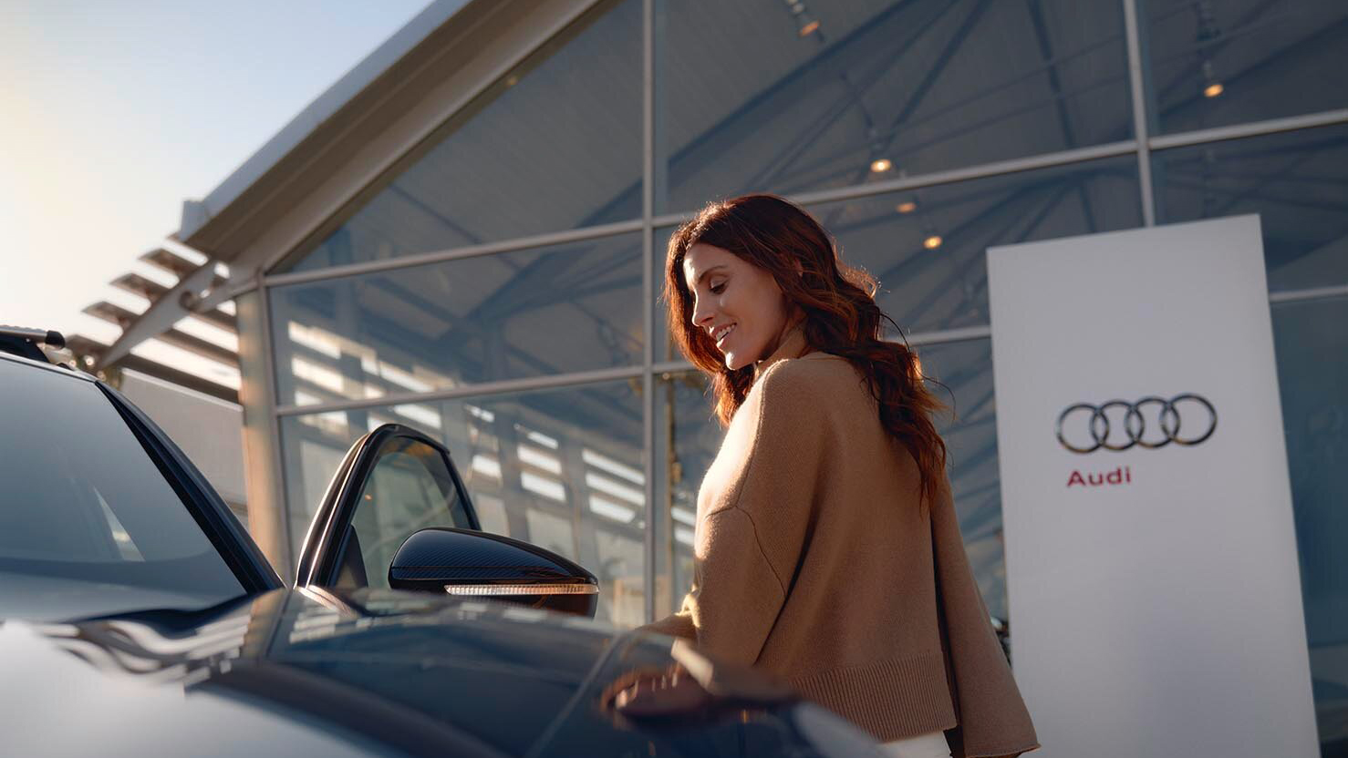 A woman getting into her Audi outside a dealership