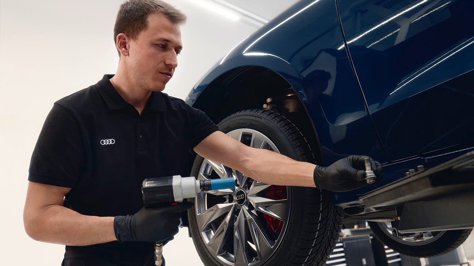 A man working on a wheel of an Audi in a workshop