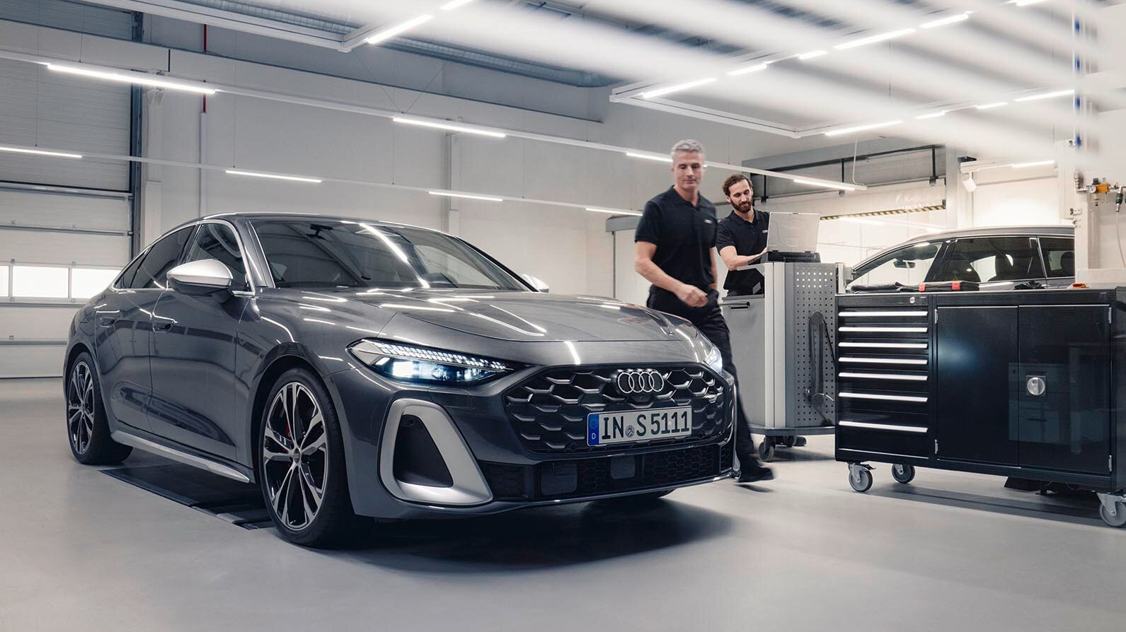 Two men working on an Audi A5 in a workshop