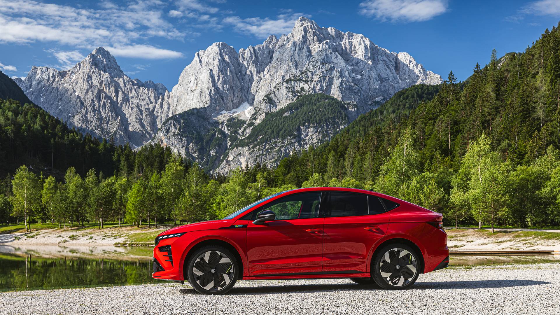 Enyaq Coupe vRS in red against a lake with a mountain in the background