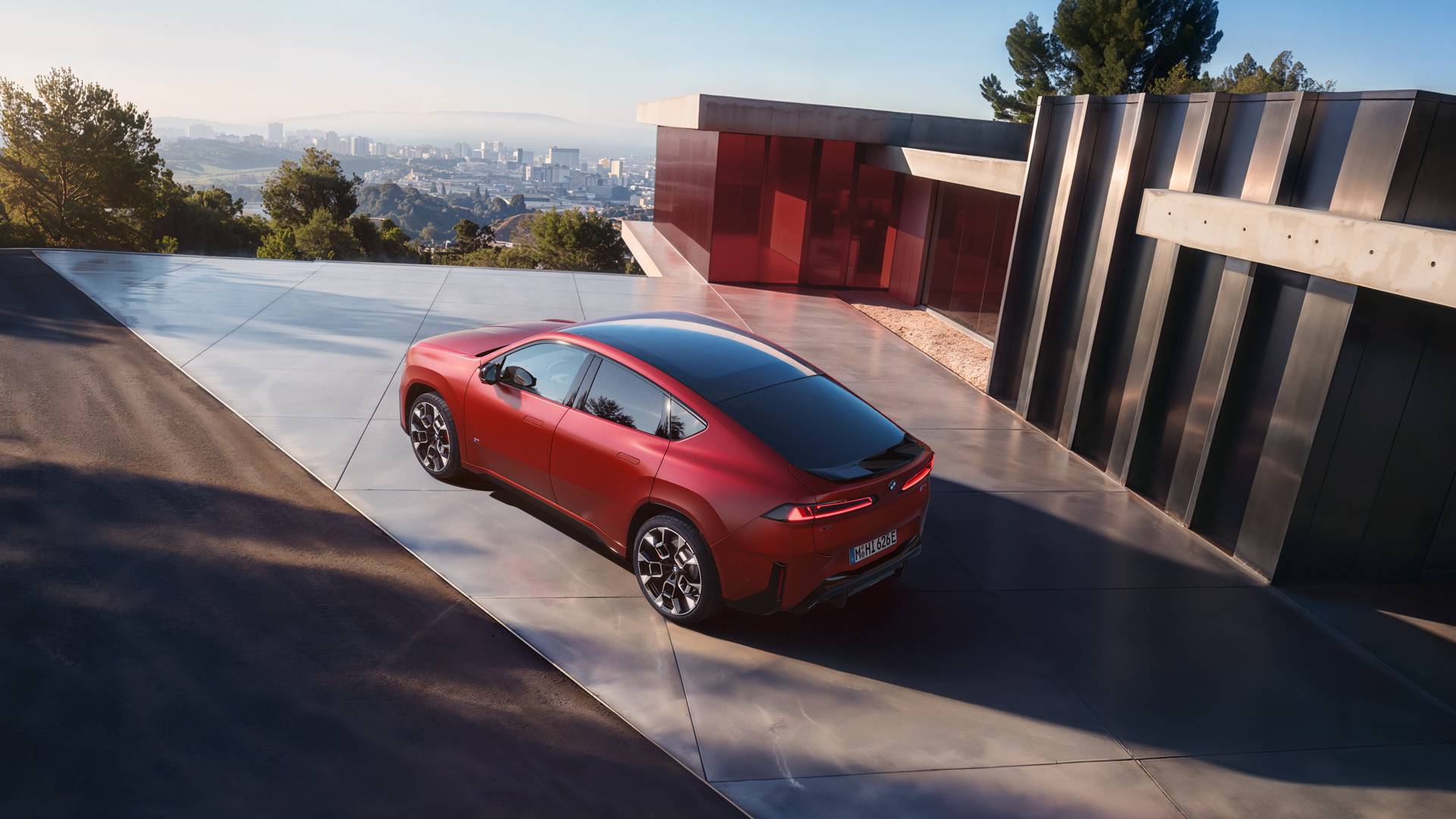 An AI generated image of a red BMW iX4 from above parked at a modern building overlooking a city