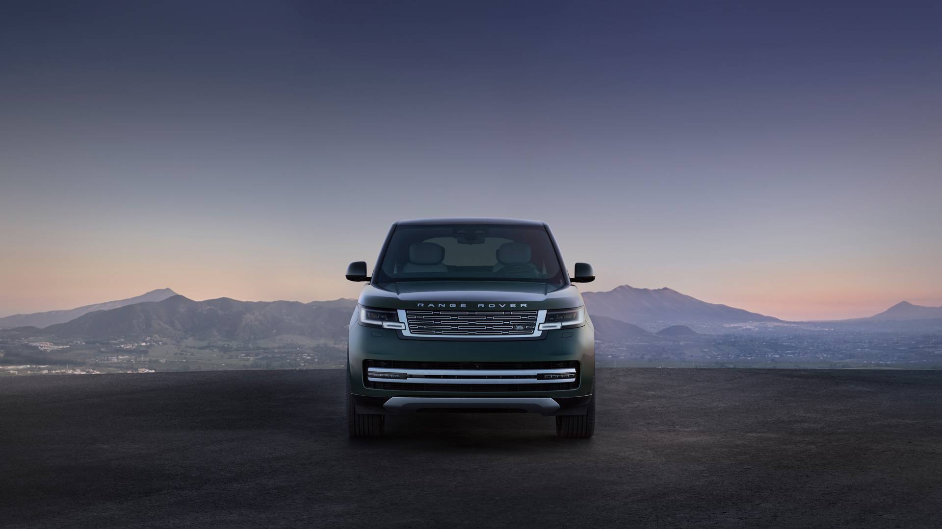 Range Rover EV over looking a mountainous town at dusk, front facing