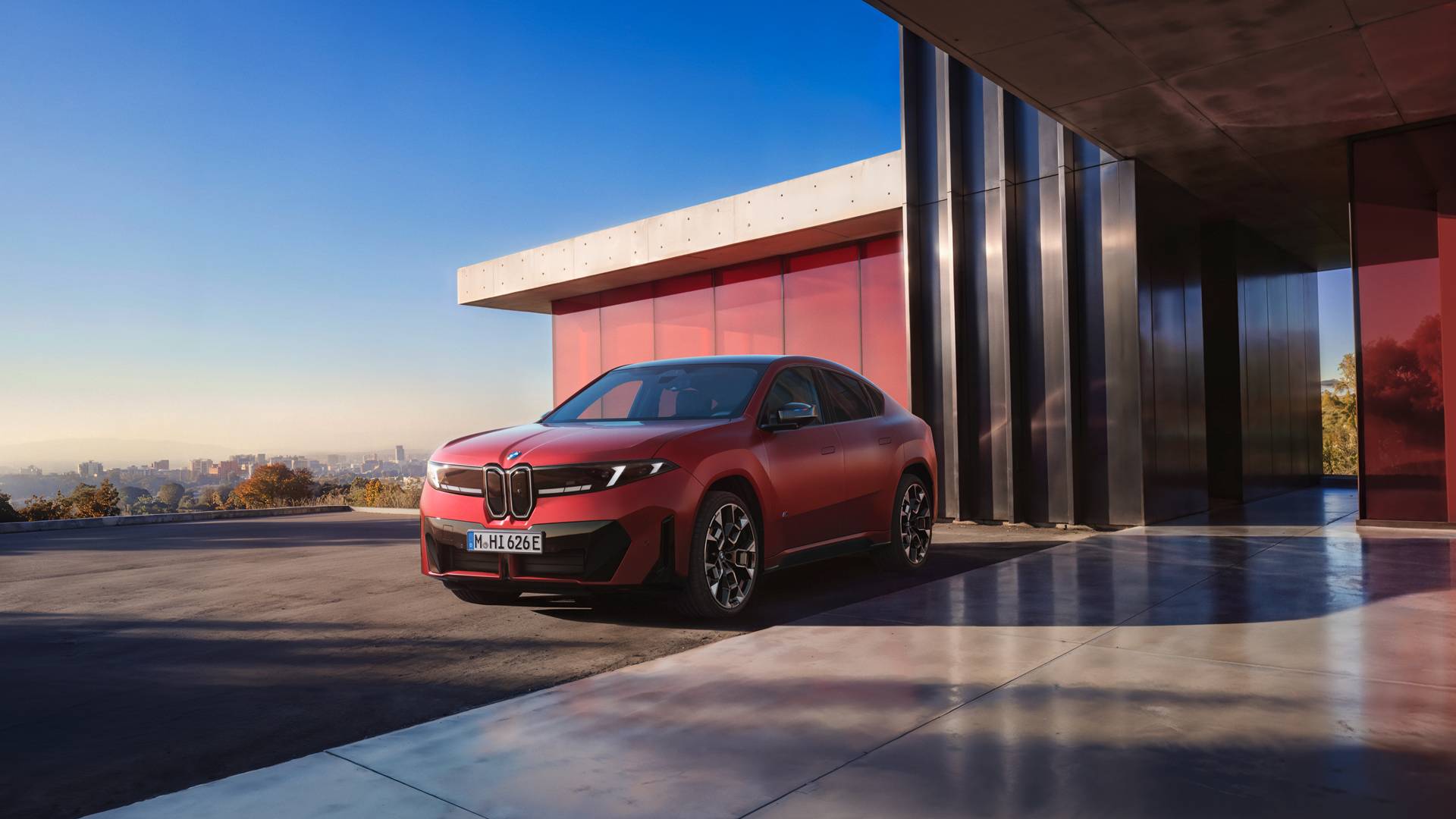 An AI generated image of a red BMW iX4 from the front at a modern building overlooking a city