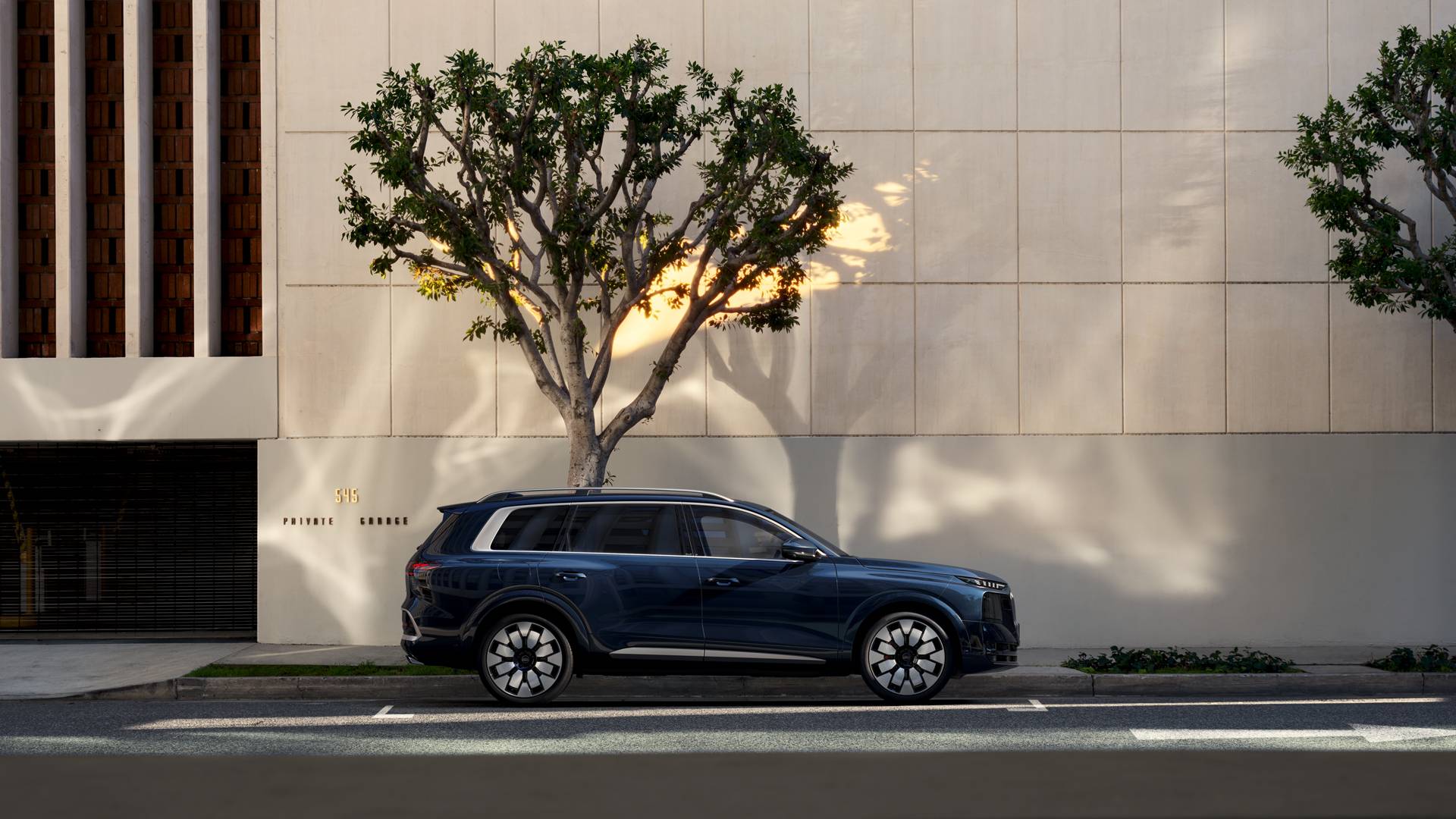 Audi Q9 in blue against a cream building
