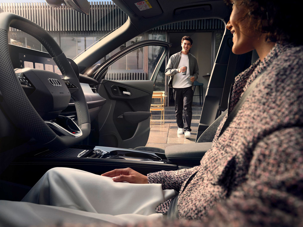 Man walking up to an Audi with an open door holding coffee