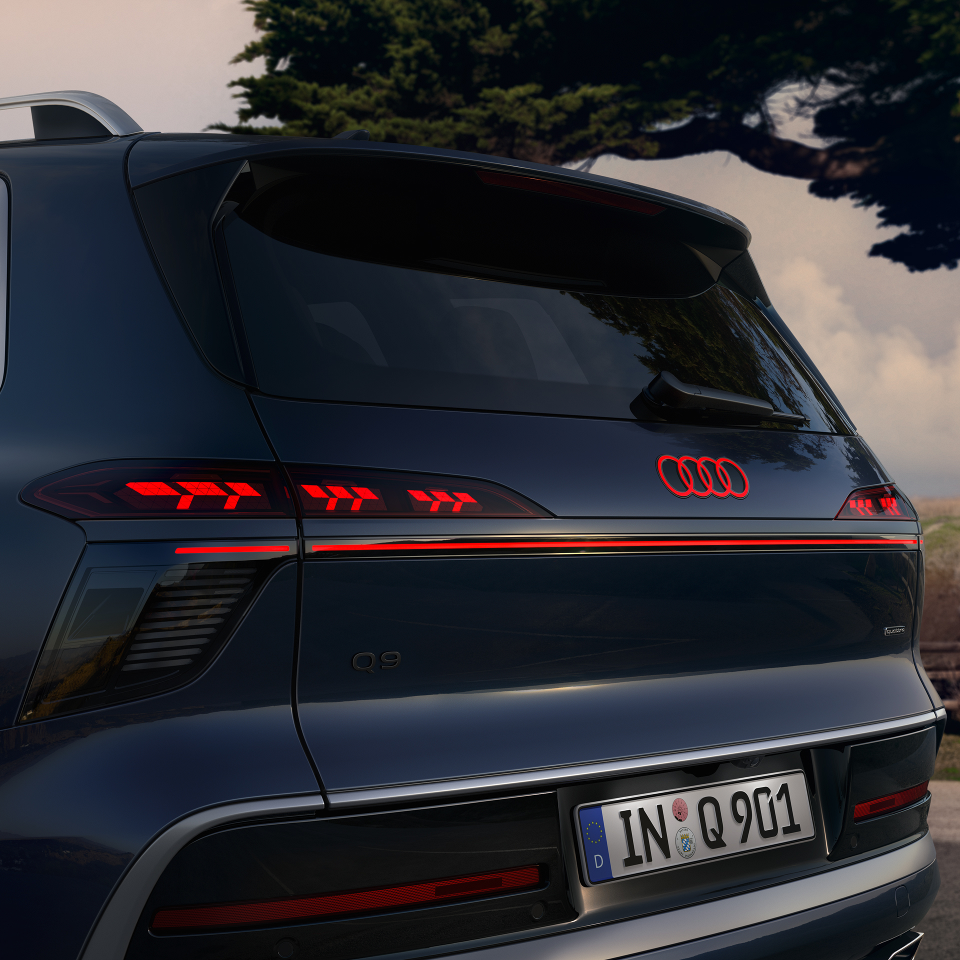 q9-exterior-2 The back of an Audi Q9 in blue with the rear lights illuminated