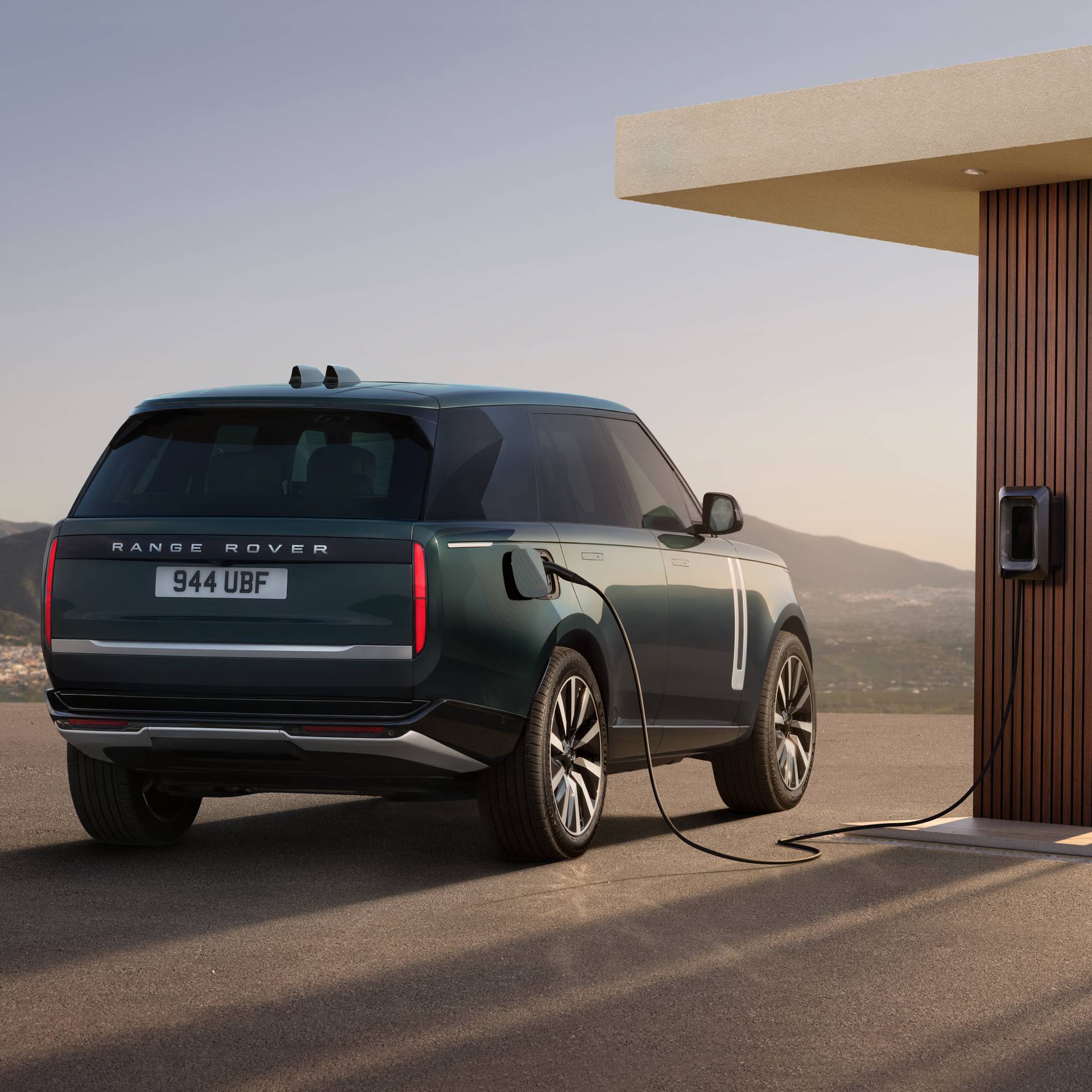Range Rover EV plugged into a charging port. Car in green