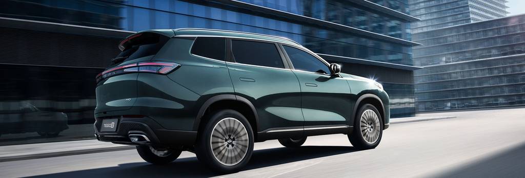 A Chery TIGGO 8 finished in dark green driving through an modern urban area