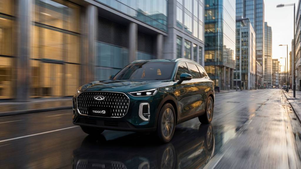 TIGGO 9 Super Hybrid in green driving on city street with tall glass fronted buildings in the background