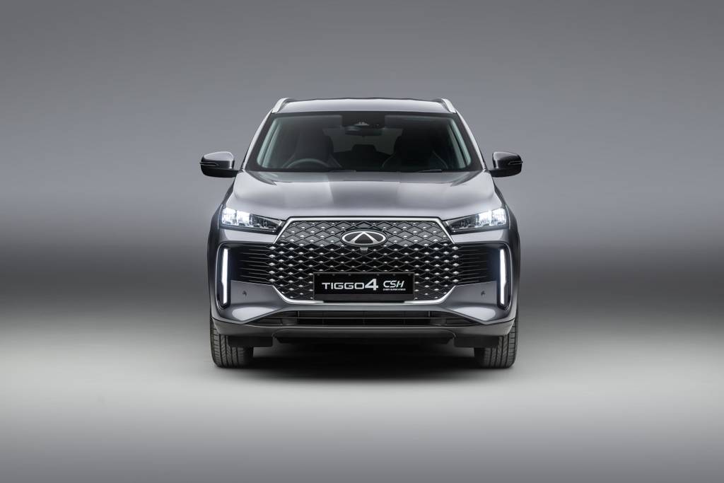 CHERY TIGGO 4 Super Hybrid front end, in a grey metallic colour with the front lights on. Parked in a studio with a grey gradient background