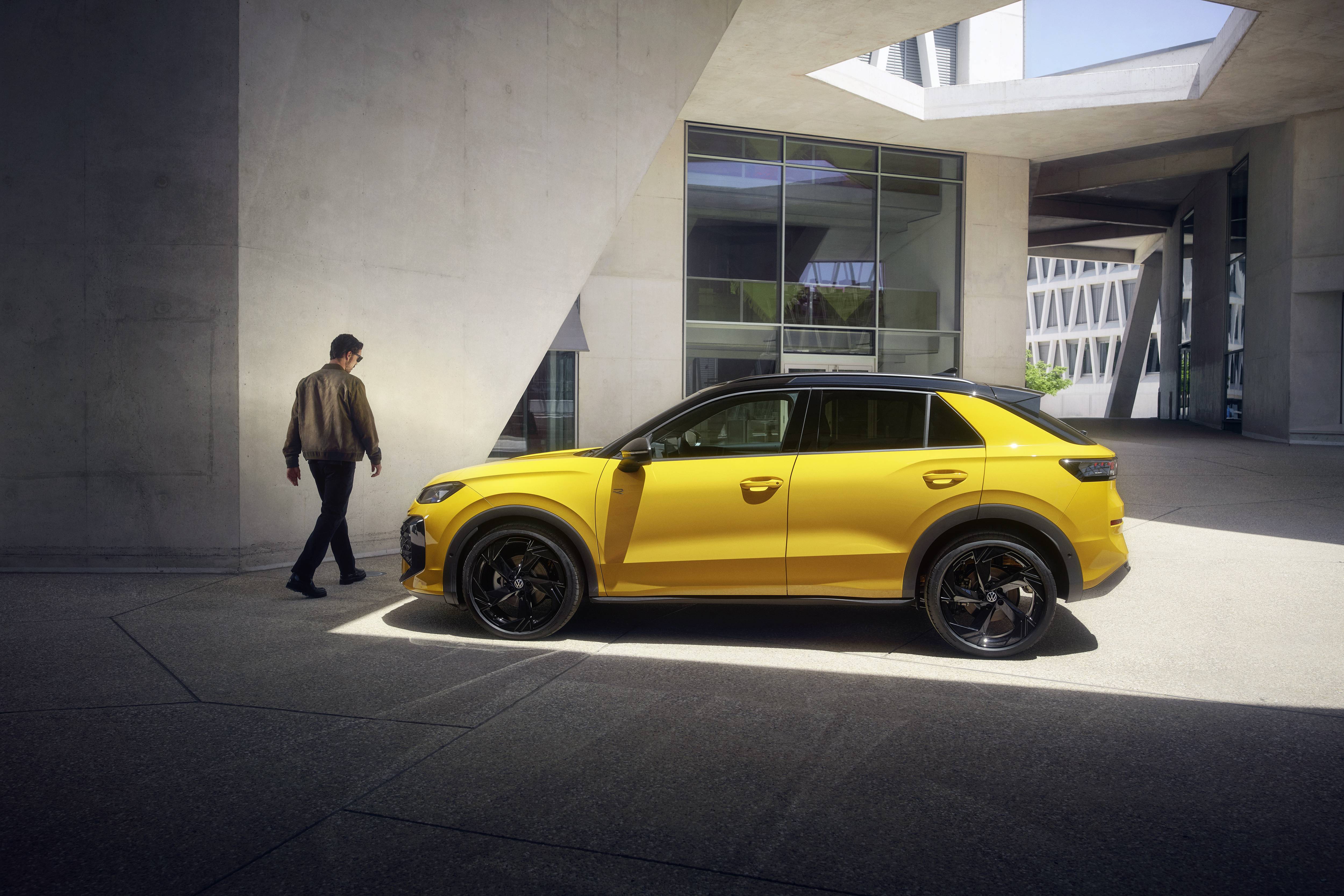 side view of T-Roc yellow parked with driver walking around the front of the vehicle
