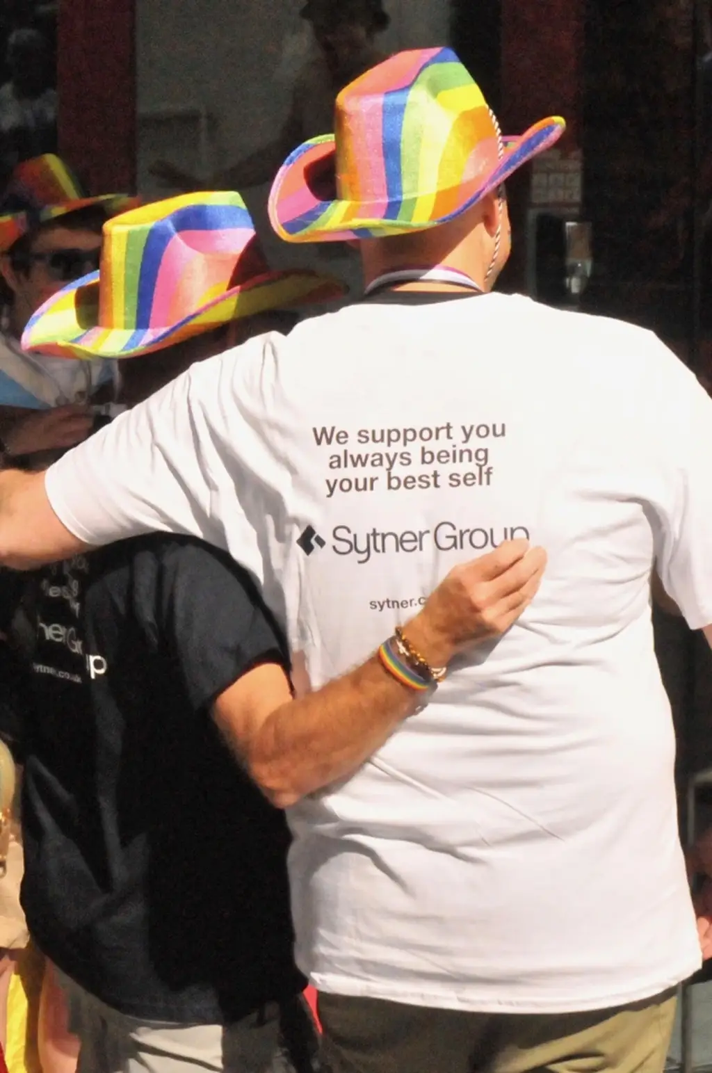 2 people stood side by side wearing multiciloured hats and wearing Sytner Branded T shirts