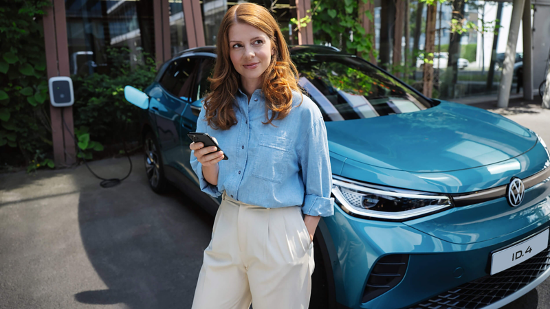 A woman lent on an ID.4 on her phone whilst the car is on charge