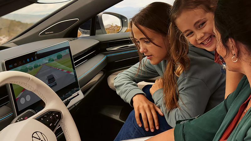 A mum and her two daughters playing on a game in an Volkswagen ID.