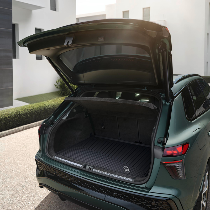 The open boot of the Audi Q3 showcasing the boot space. The car sits in front of a residential building