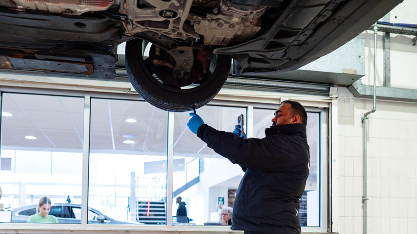 Man videoing himself measuring the tyre tread on a Volkswagen in a workshop