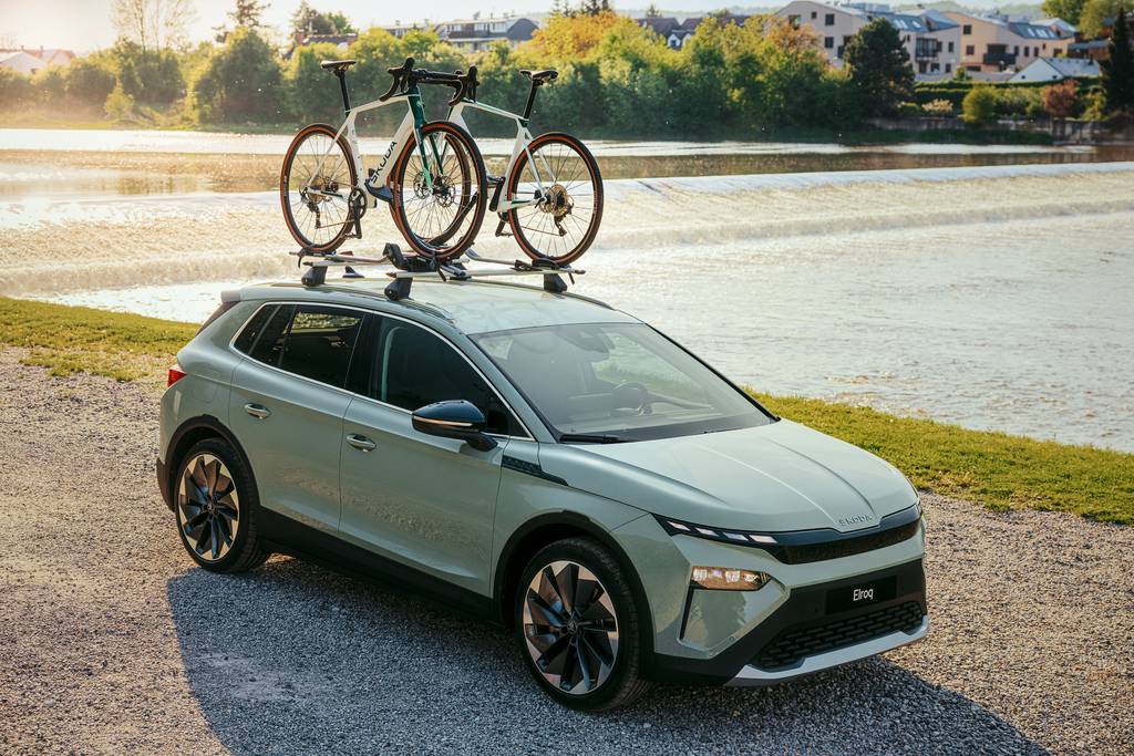 skoda elroq parked in front of a river at sunset with a bike rack on its roof