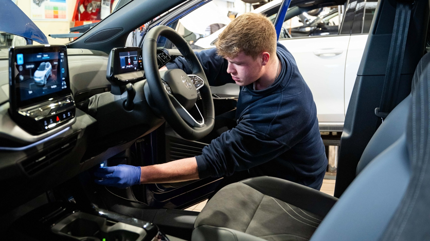 A man in the footwell of a Volkswagen running a diagnostics check in a workshop