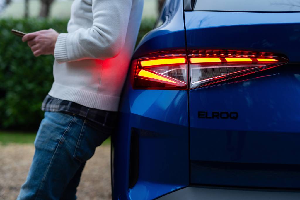 man leaning on rear side of blue Elroq Sportline