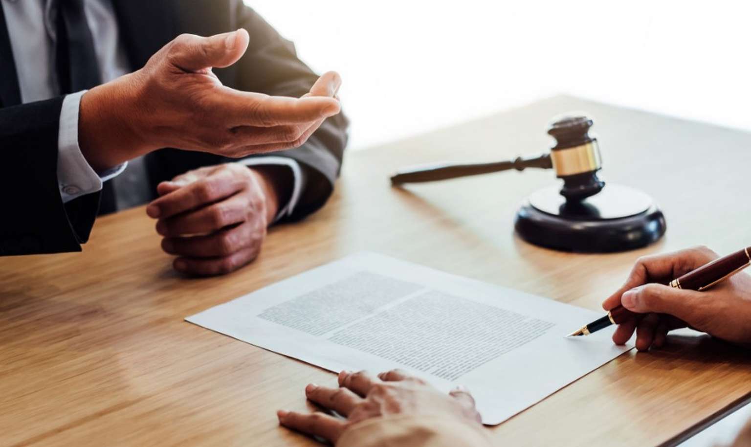 person signing a document at a desk with a lawyer 