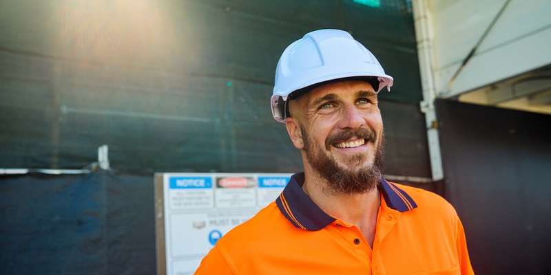 Australian tradesman smiling with bright orange vest