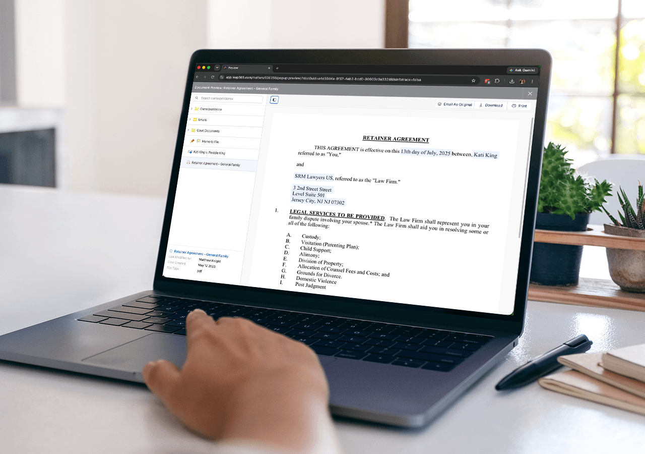 Person viewing a retainer agreement document on a laptop, with a hand on the keyboard, next to a notebook and plants.
