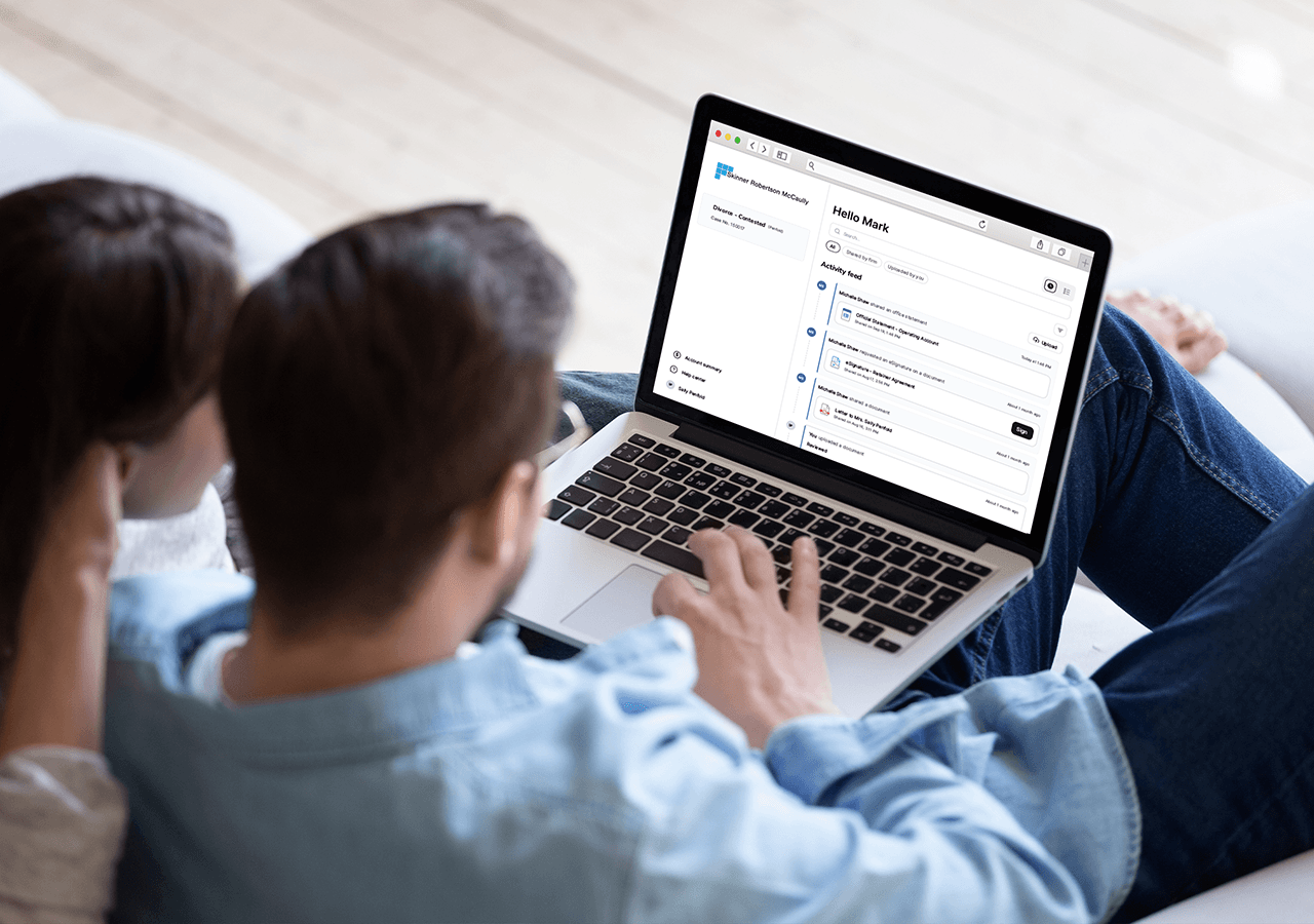 Man sitting and using a laptop on his lap, displaying the LawConnect client portal. A woman is beside him, looking at the screen.