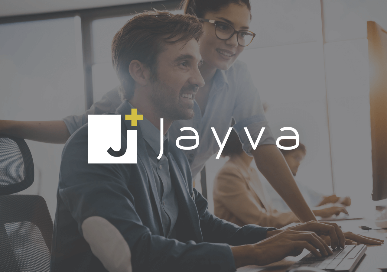 Two people smiling and working at a computer in an office setting, with the Jayva logo overlaid on the image.