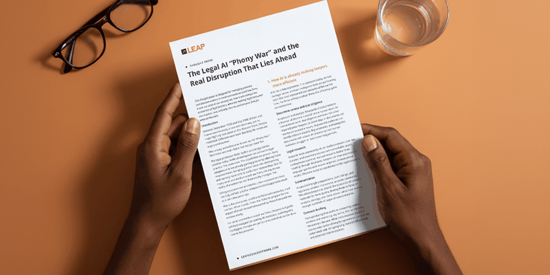 Hands holding a document titled "The Legal AI 'Phony War'" on a desk with a pair of glasses and a glass of water.