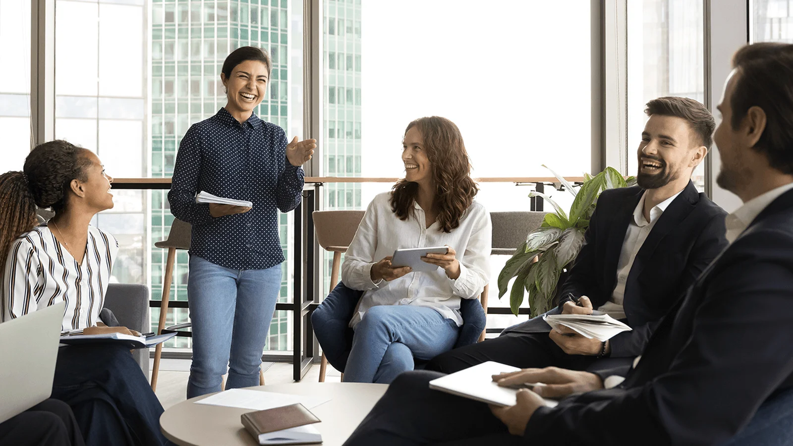 A diverse group of professionals, seated in a modern office setting, engaged in a lively and casual discussion.